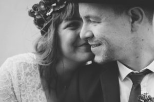 Emotionale Nahaufnahme in Schwarz-Weiß: Die Braut lehnt sich zärtlich an den Bräutigam, beide lächeln mit geschlossenen Augen – festgehalten bei einer Hochzeit in Rostock.