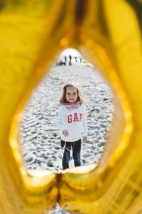 Ein Kind hält einen Luftballon am Strand von Markgrafenheide Strandfoto mit Kind in Rostock – Blick durch die Jubiläumszahl 0