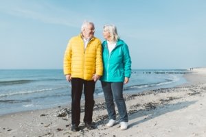 Paarfoto zur goldenen Hochzeit – Hand in Hand am Strand von Rostock Ein älteres Ehepaar steht Hand in Hand am Strand von Rostock, lächelt sich liebevoll an und genießt den Moment beim Familienshooting zur goldenen Hochzeit bei sonnigem Wetter.